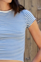 Woman wearing BRISA French terry stripe crewneck short sleeve top featuring soft stretch French terry fabric, classic crewneck design, contrast neckband detail, slim fitted short sleeves, timeless yarn dye stripe pattern, and semi cropped length for easy everyday styling.