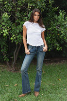 Woman wearing LENI cotton slub lettuce hem baby tee featuring soft lightweight cotton slub fabric, classic crew neckline, short cap sleeves, fitted baby tee silhouette, slightly cropped length, and delicate lettuce edge hem for effortless casual styling with denim.