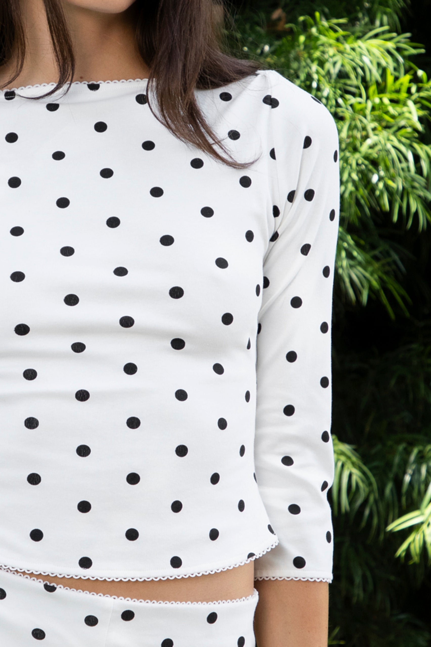 Woman wearing MARLIE polka dot quarter sleeve top featuring soft cotton blend stretch jersey fabric, allover polka dot print, classic boat neckline with delicate picot trim, fitted silhouette, three quarter length sleeves with picot trim cuffs, and slightly cropped length designed to pair with the matching MARIE capri pants.