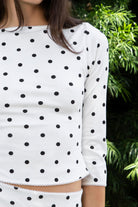 Woman wearing MARLIE polka dot quarter sleeve top featuring soft cotton blend stretch jersey fabric, allover polka dot print, classic boat neckline with delicate picot trim, fitted silhouette, three quarter length sleeves with picot trim cuffs, and slightly cropped length designed to pair with the matching MARIE capri pants.