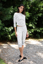 Woman wearing MARLIE polka dot quarter sleeve top featuring soft cotton blend stretch jersey fabric, allover polka dot print, classic boat neckline with delicate picot trim, fitted silhouette, three quarter length sleeves with picot trim cuffs, and slightly cropped length designed to pair with the matching MARIE capri pants.