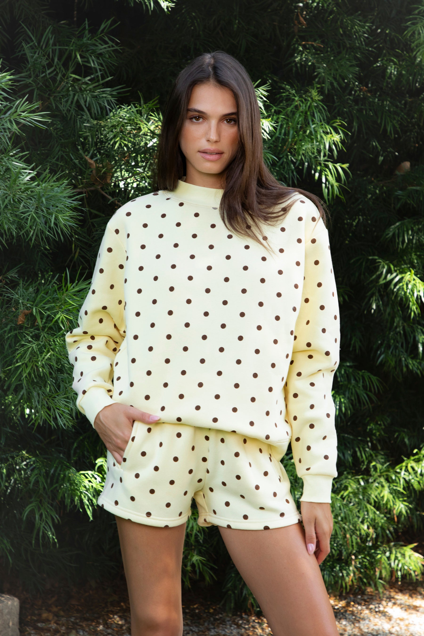 Woman wearing PIPPA polka dot plush fleece mock neck sweatshirt featuring soft cotton blend fleece fabric, allover polka dot print, classic crew neckline with ribbed trim, relaxed silhouette, long sleeves with dropped shoulders, ribbed cuffs and hem, and cozy construction designed to pair with the matching PIPPA shorts.