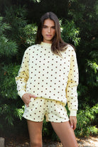 Woman wearing PIPPA polka dot plush fleece mock neck sweatshirt featuring soft cotton blend fleece fabric, allover polka dot print, classic crew neckline with ribbed trim, relaxed silhouette, long sleeves with dropped shoulders, ribbed cuffs and hem, and cozy construction designed to pair with the matching PIPPA shorts.