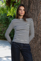 Woman wearing ROSLYN striped boat neck long sleeve top featuring soft brushed cotton stretch jersey fabric, classic horizontal stripe pattern, wide boat neckline that can be styled on or slightly off the shoulder, fitted silhouette, slim full length sleeves, and hip length hem for easy everyday styling.