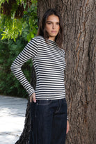 Woman wearing ROSLYN striped boat neck long sleeve top featuring soft brushed cotton stretch jersey fabric, classic horizontal stripe pattern, wide boat neckline that can be styled on or slightly off the shoulder, fitted silhouette, slim full length sleeves, and hip length hem for easy everyday styling.