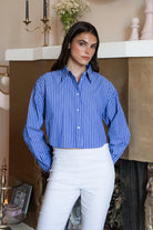 Woman wearing HAMPTON classic stripe collared cropped poplin shirt featuring classic stripe cotton fabric, crisp point collar, button front closure, ultra cropped relaxed silhouette, dropped shoulders, long sleeves with button cuffs, and clean back yoke detail for a polished modern tailored look.