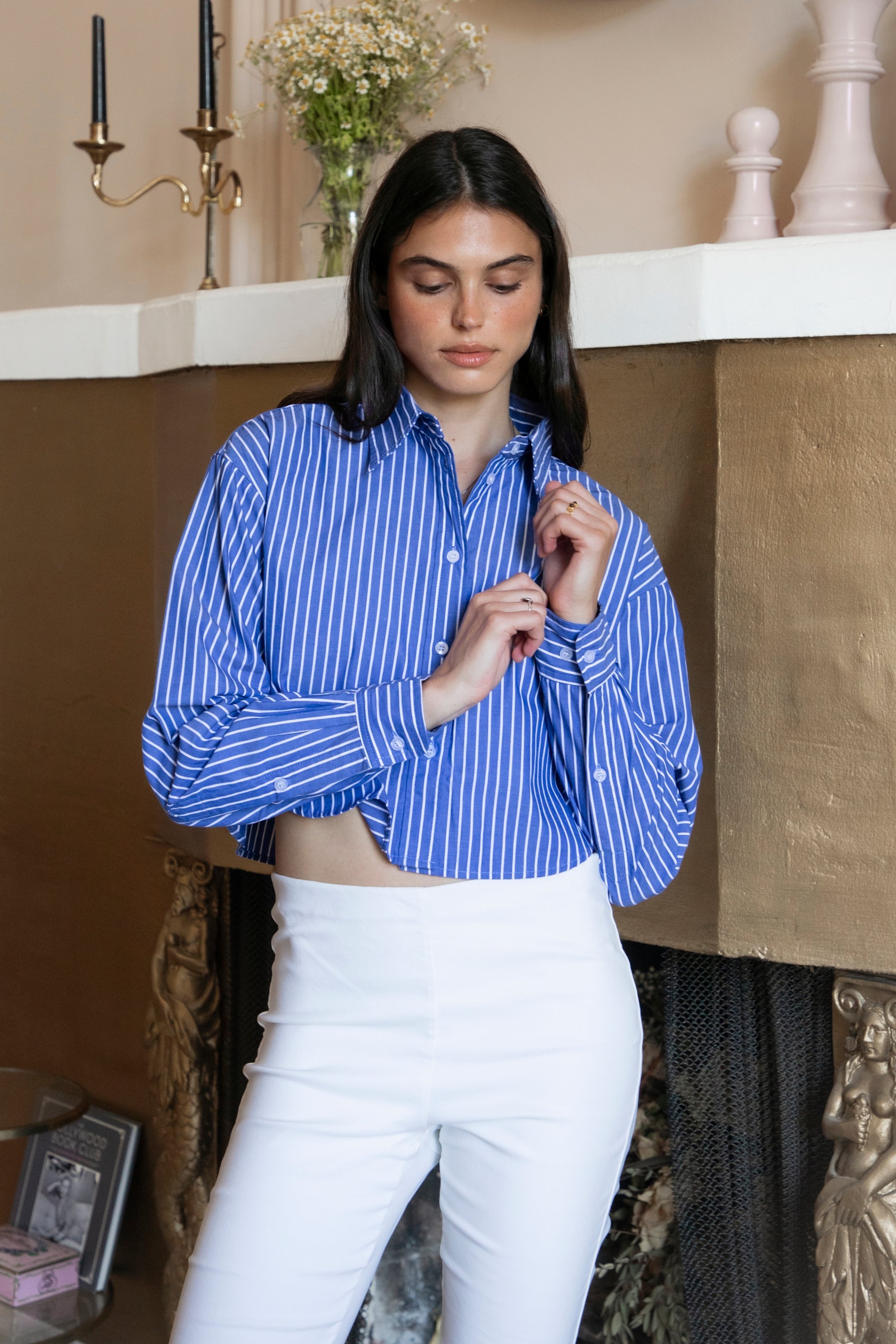 Woman wearing HAMPTON classic stripe collared cropped poplin shirt featuring classic stripe cotton fabric, crisp point collar, button front closure, ultra cropped relaxed silhouette, dropped shoulders, long sleeves with button cuffs, and clean back yoke detail for a polished modern tailored look.