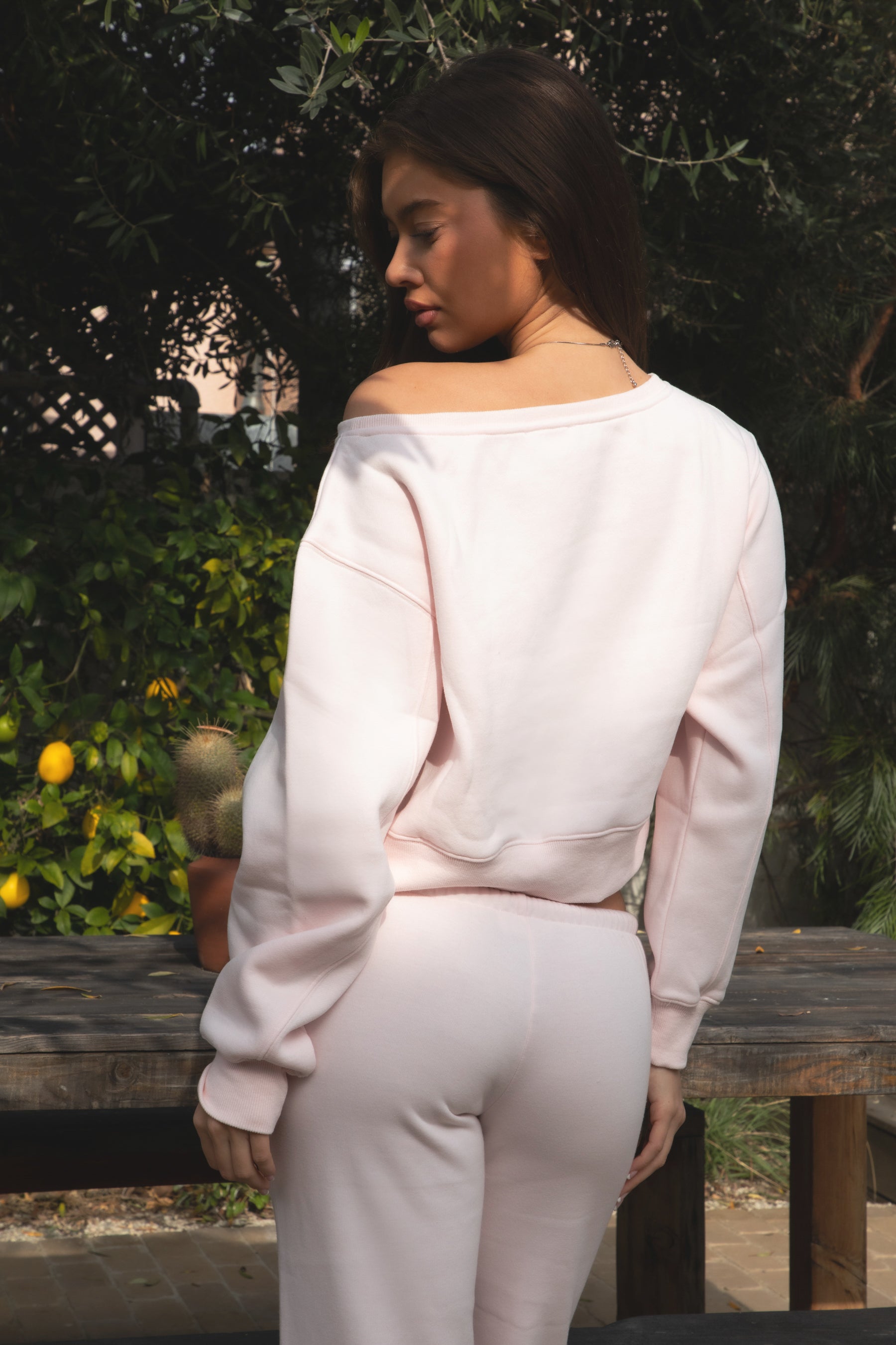 Woman wearing TIC TOC TJ31006-LANA LANA lightweight cloud fleece off-the-shoulder sweater featuring an asymmetric ribbed neckline worn off one shoulder, cropped slouchy fit, dropped armholes, and stretch ribbed cuffs, styled with relaxed wide leg fleece pants for a cozy lounge and travel-ready look.