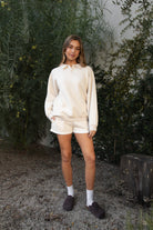 Woman wearing TIC TOC TJ31645-ARDYN ARDYN classic polo collar long sleeve top featuring a two-button front placket, drop shoulder relaxed sleeves, easy loose fit, and ribbed cuffs and hem, styled with simple bottoms for a cozy off-duty everyday look.