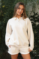 Woman wearing TIC TOC TJ31645-ARDYN ARDYN classic polo collar long sleeve top featuring a two-button front placket, drop shoulder relaxed sleeves, easy loose fit, and ribbed cuffs and hem, styled with simple bottoms for a cozy off-duty everyday look.