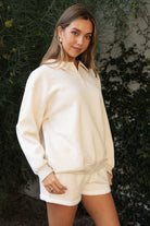Woman wearing TIC TOC TJ31645-ARDYN ARDYN classic polo collar long sleeve top featuring a two-button front placket, drop shoulder relaxed sleeves, easy loose fit, and ribbed cuffs and hem, styled with simple bottoms for a cozy off-duty everyday look.