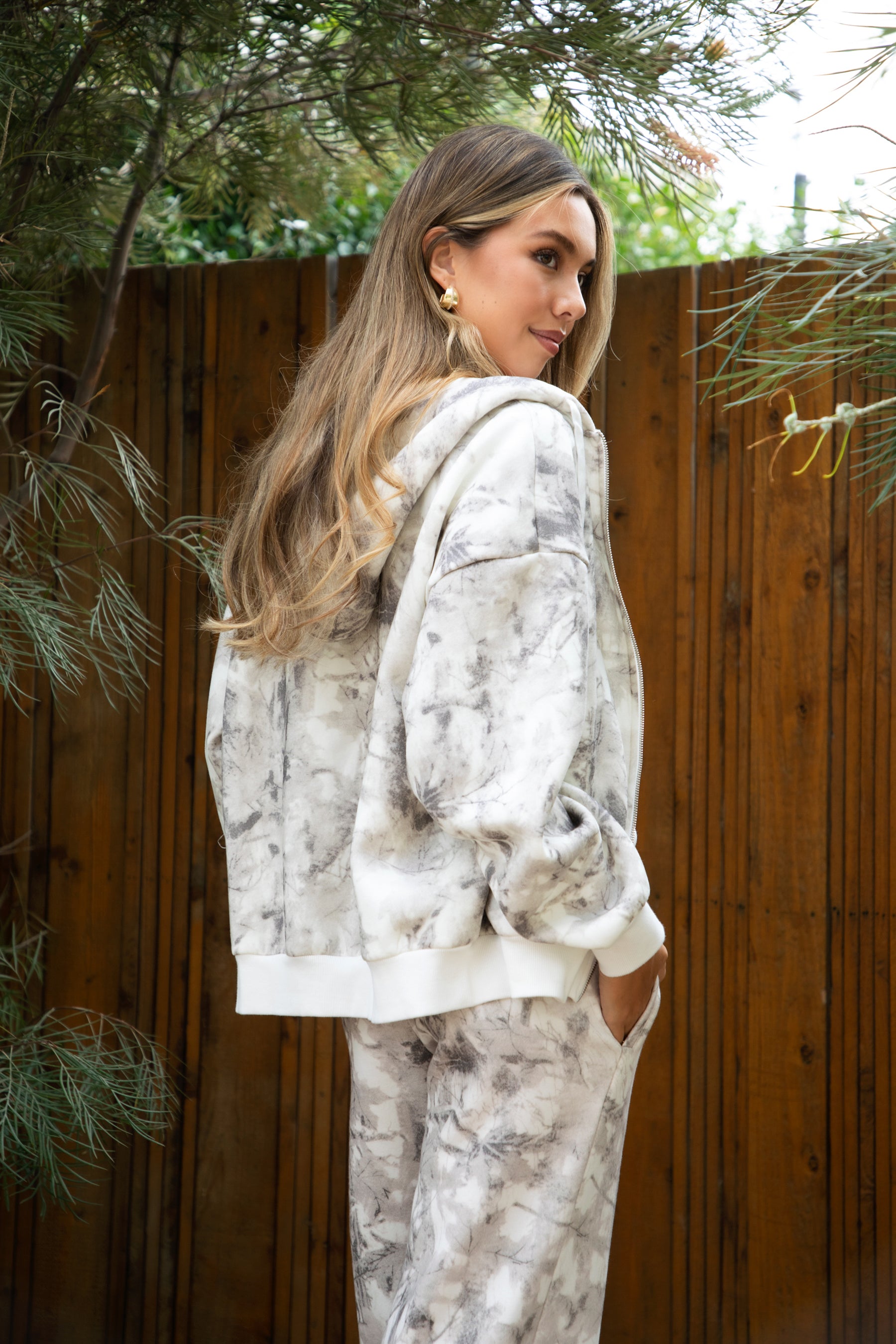 Woman wearing TIC TOC TJ31822-AVERY-JK AVERY light camo wood fleece classic oversized hoodie featuring a relaxed zip-up front, attached hood with adjustable drawstrings, front kangaroo pocket, and ribbed cuffs and hem, styled with casual bottoms for a cozy off-duty lounge and streetwear look.