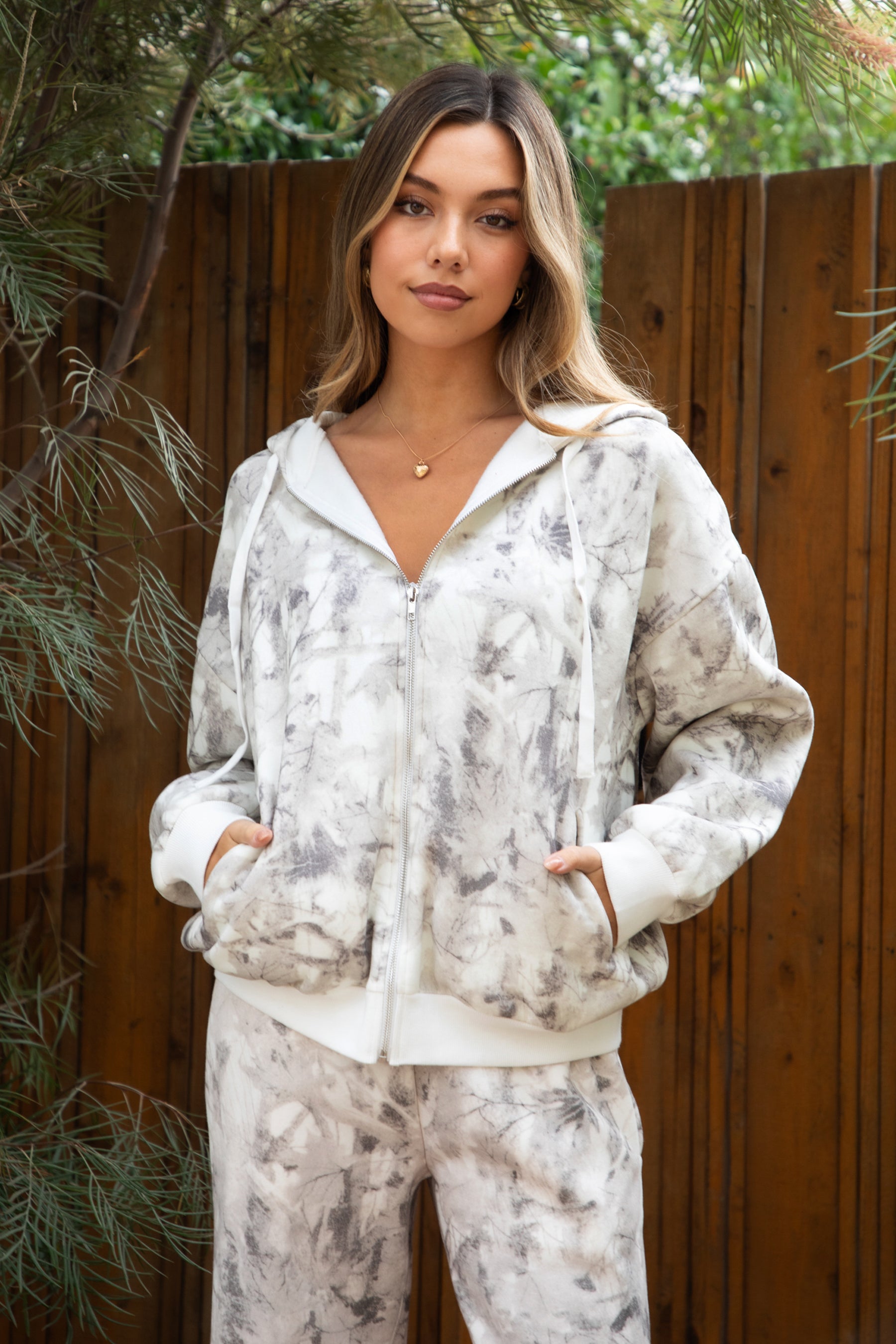 Woman wearing TIC TOC TJ31822-AVERY-JK AVERY light camo wood fleece classic oversized hoodie featuring a relaxed zip-up front, attached hood with adjustable drawstrings, front kangaroo pocket, and ribbed cuffs and hem, styled with casual bottoms for a cozy off-duty lounge and streetwear look.