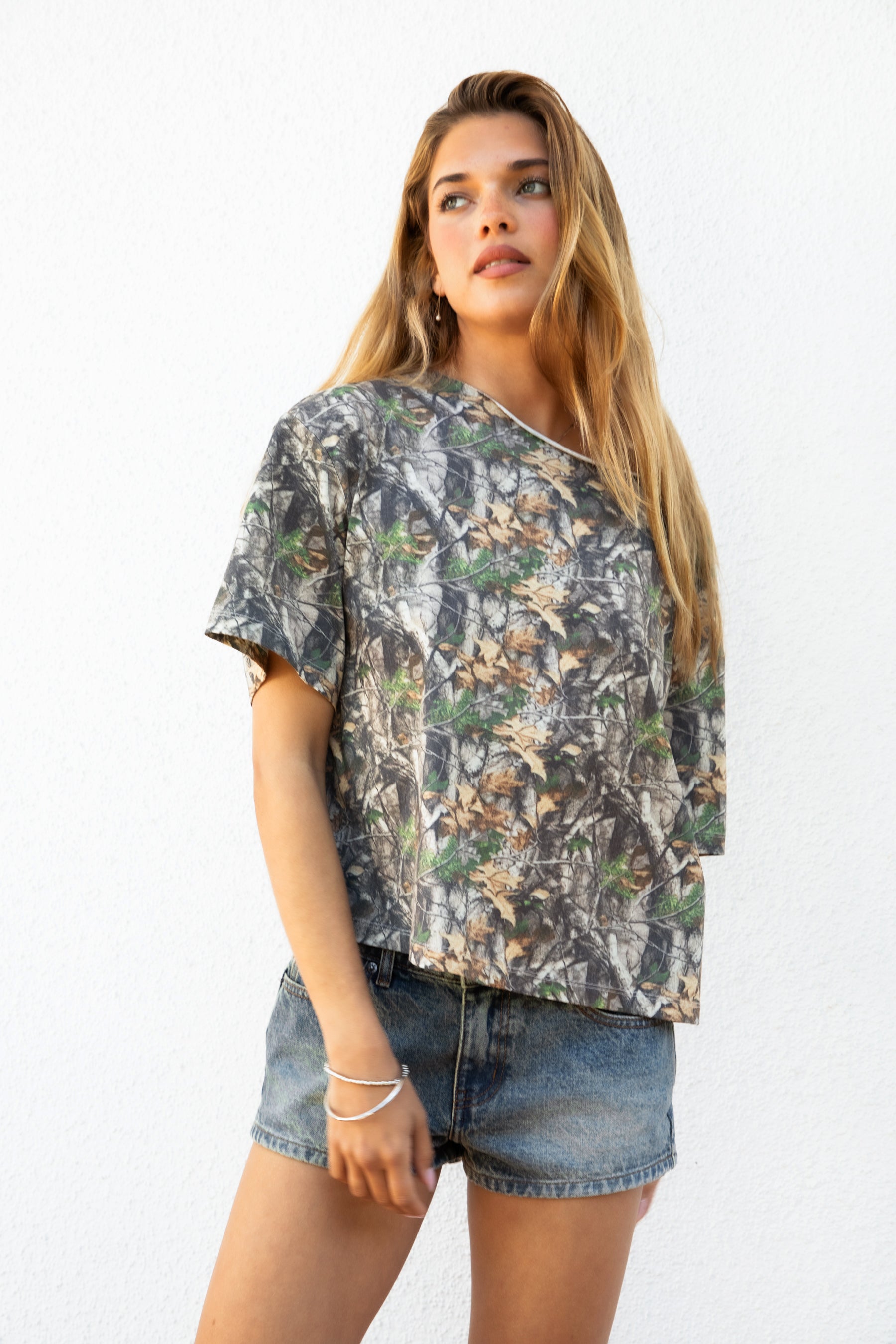 Woman wearing BAYOU camo print oversized one shoulder T-shirt featuring soft washed cotton jersey fabric, oversized slouchy silhouette, asymmetrical neckline, woodland camo print, and loose short sleeves for relaxed off-duty styling.