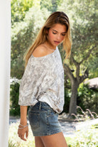 Woman wearing ROGUE light camo print oversized T-shirt featuring a relaxed oversized silhouette, asymmetrical one-shoulder styling, muted camo print, loose short sleeves, and lightweight stretch fabric for effortless off-duty streetwear styling.