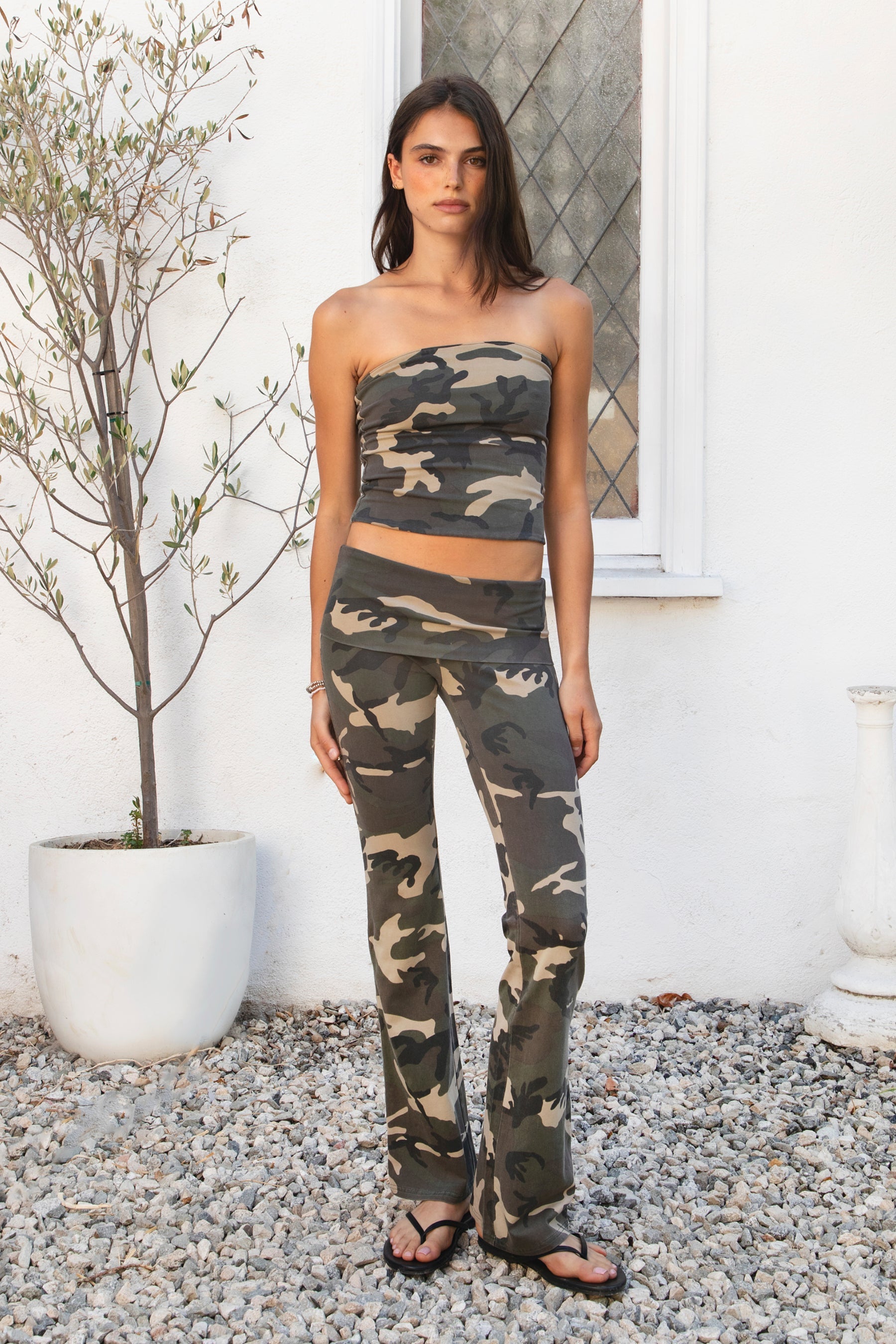 Woman wearing REMI dark military camo classic cropped tube top featuring soft stretch cotton jersey fabric, allover woodland camouflage print, classic strapless tube neckline, fitted body hugging silhouette, garment washed finish, and cropped length perfect for matching camo sets and low rise bottoms.