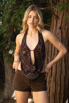 Woman wearing VEDA beaded embroidered cowl halter top featuring a deep draped cowl neckline, halter neck with self tie closure, floral beaded and sequin embroidery at the front, front bust strap detail, open back with adjustable strap, and lightweight sheer chiffon fabric.