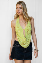 Woman wearing VEDA beaded embroidered cowl halter top featuring a deep draped cowl neckline, halter neck with self tie closure, floral beaded and sequin embroidery at the front, front bust strap detail, open back with adjustable strap, and lightweight sheer chiffon fabric.