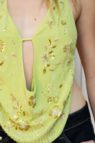Woman wearing VEDA beaded embroidered cowl halter top featuring a deep draped cowl neckline, halter neck with self tie closure, floral beaded and sequin embroidery at the front, front bust strap detail, open back with adjustable strap, and lightweight sheer chiffon fabric.