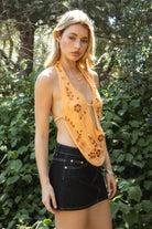 Woman wearing VEDA beaded embroidered cowl halter top featuring a deep draped cowl neckline, halter neck with self tie closure, floral beaded and sequin embroidery at the front, front bust strap detail, open back with adjustable strap, and lightweight sheer chiffon fabric.