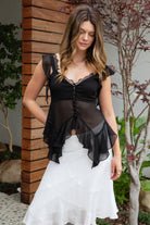 Woman wearing AMORIA lace trim sheer chiffon peplum top featuring a romantic lace trim V neckline, covered button front, sheer chiffon fabric with jersey bust lining, asymmetrical flutter ruffle sleeves, layered peplum hem, and smocked back panel for flexible feminine styling.