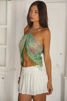 Woman wearing TIC TOC TL31629-SERAYA SERAYA beaded tassel embellished mesh halter scarf top featuring sheer embroidered mesh fabric with floral appliqué and sequin accents, beaded tassel fringe along the hem, halter neck tie closure, and an open back with adjustable tie, styled over a simple bralette and low-rise bottoms for a bold festival and resort-ready statement look.