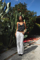 Woman wearing TIC TOC TL31684 AURYA chiffon sequin beaded cowl neck top featuring a draped cowl neckline, floral sequin and beaded embroidery, thin adjustable straps with cross back detail, fitted cropped silhouette, and asymmetrical hemline for a feminine festival and night-out look.