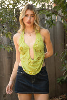 Woman wearing SURA beaded embroidered halter neck top featuring a deep draped cowl neckline, halter neck with self tie closure, floral beaded and sequin embroidery, front bust strap detail, open back with adjustable strap, and lightweight sheer chiffon fabric.