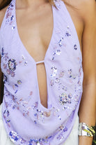 Woman wearing SURA beaded embroidered halter neck top featuring a deep draped cowl neckline, halter neck with self tie closure, floral beaded and sequin embroidery, front bust strap detail, open back with adjustable strap, and lightweight sheer chiffon fabric.