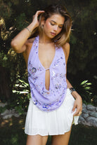 Woman wearing SURA beaded embroidered halter neck top featuring a deep draped cowl neckline, halter neck with self tie closure, floral beaded and sequin embroidery, front bust strap detail, open back with adjustable strap, and lightweight sheer chiffon fabric.