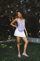 Woman wearing SURA beaded embroidered halter neck top featuring a deep draped cowl neckline, halter neck with self tie closure, floral beaded and sequin embroidery, front bust strap detail, open back with adjustable strap, and lightweight sheer chiffon fabric.