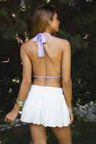 Woman wearing SURA beaded embroidered halter neck top featuring a deep draped cowl neckline, halter neck with self tie closure, floral beaded and sequin embroidery, front bust strap detail, open back with adjustable strap, and lightweight sheer chiffon fabric.