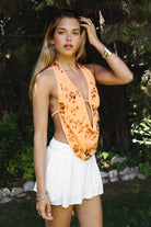 Woman wearing SURA beaded embroidered halter neck top featuring a deep draped cowl neckline, halter neck with self tie closure, floral beaded and sequin embroidery, front bust strap detail, open back with adjustable strap, and lightweight sheer chiffon fabric.