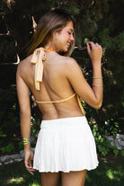 Woman wearing SURA beaded embroidered halter neck top featuring a deep draped cowl neckline, halter neck with self tie closure, floral beaded and sequin embroidery, front bust strap detail, open back with adjustable strap, and lightweight sheer chiffon fabric.