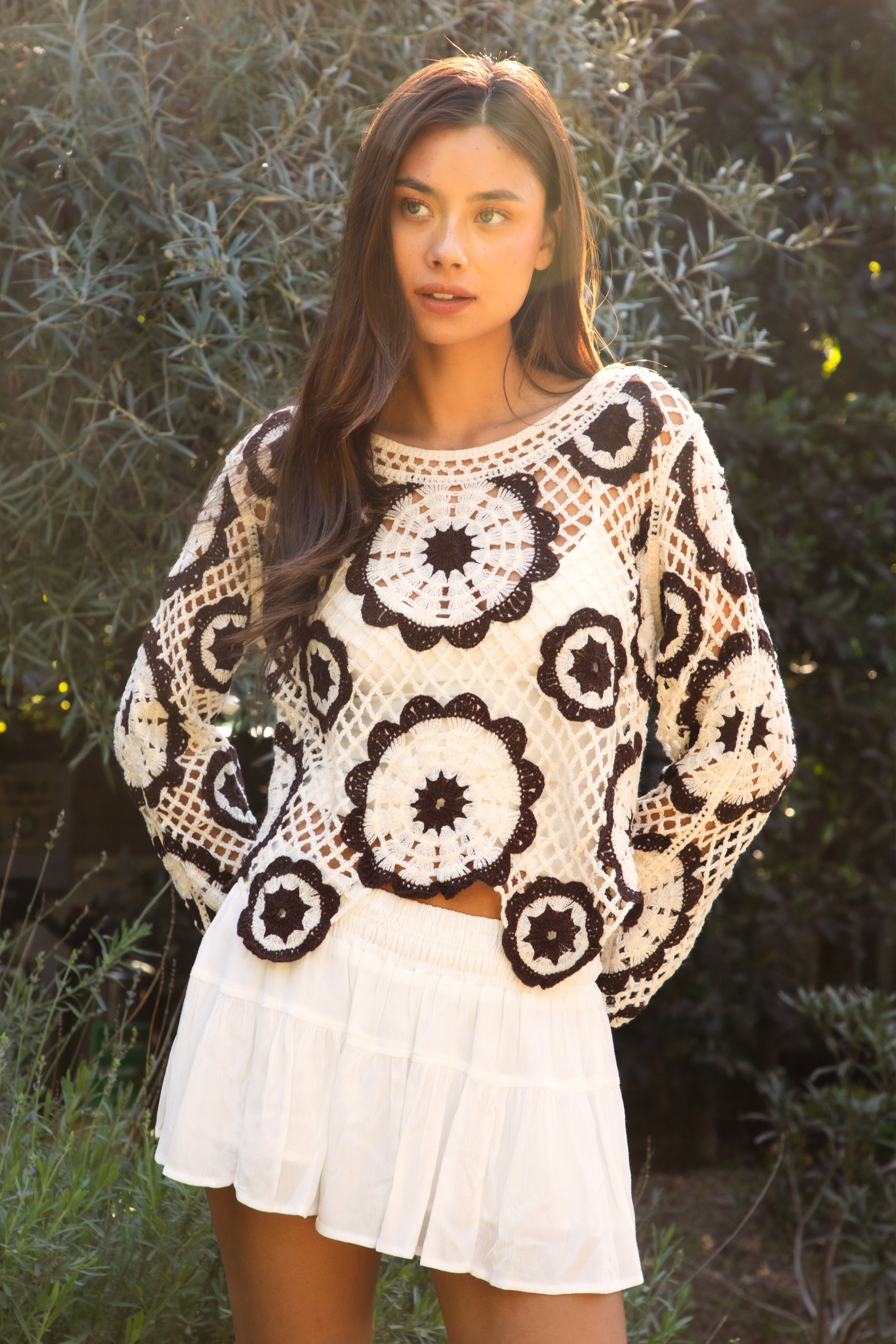 Woman wearing TIC TOC TL31962-SOLANDRA SOLANDRA crochet long sleeve cover up top featuring an open crochet mandala flower pattern in contrast cream and brown circular design, wide round neckline, relaxed easy fit silhouette, and long bell sleeves with lightweight open knit texture, styled over a simple bralette and bottoms for a boho festival and resort-ready look.