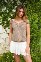 Woman wearing MAREN gingham off shoulder ruffle cap sleeve top featuring a soft ruffle neckline, ruched bust detail, functional button front, smocked back panel, ruffled peplum hem, and lightweight cotton gingham fabric for feminine summer styling.