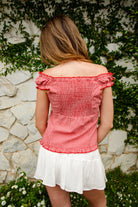 Woman wearing MAREN gingham off shoulder ruffle cap sleeve top featuring a soft ruffle neckline, ruched bust detail, functional button front, smocked back panel, ruffled peplum hem, and lightweight cotton gingham fabric for feminine summer styling.