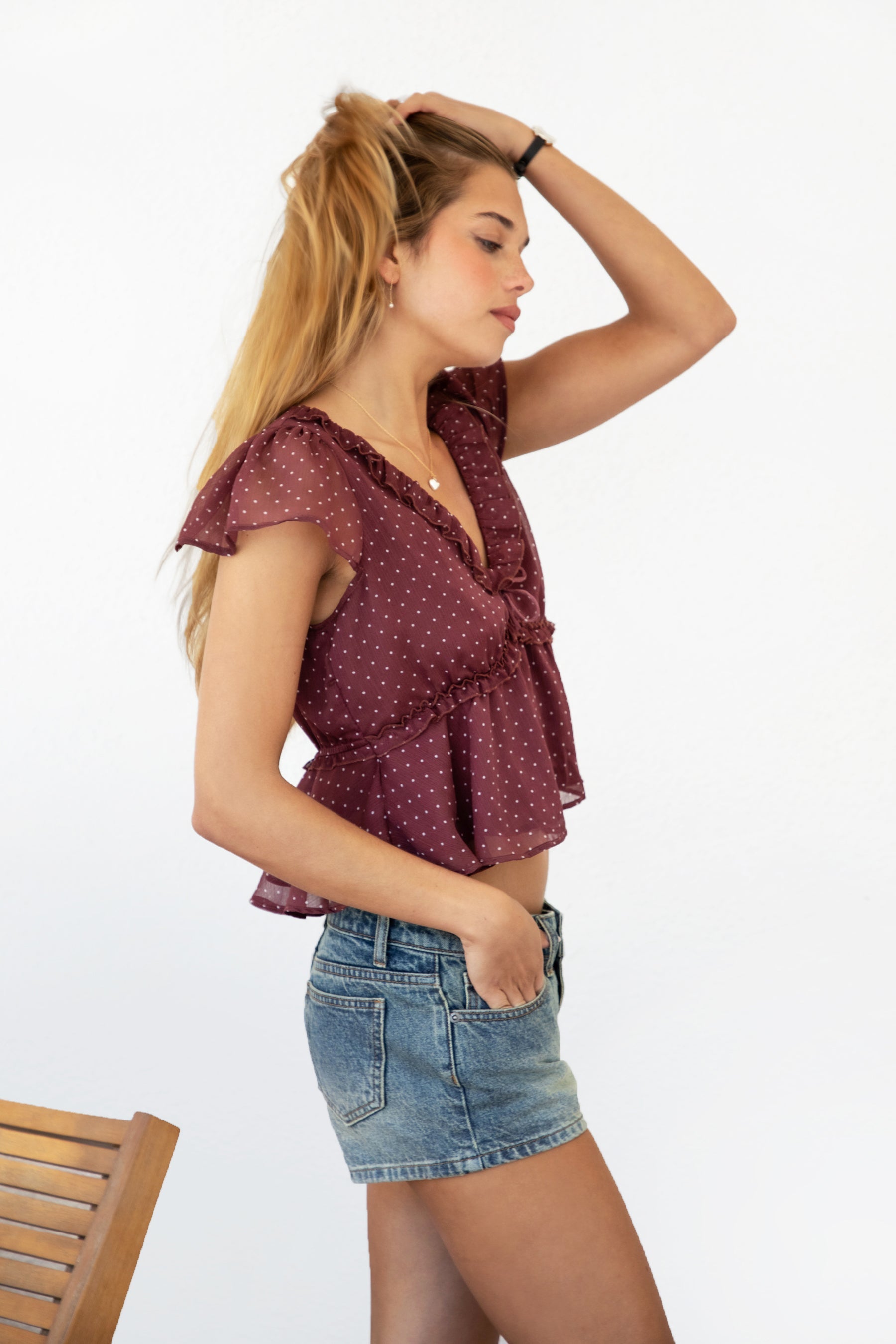 Woman wearing WYNONA polka dot chiffon crop top featuring lightweight printed chiffon, V-neckline with ruffle trim, flutter sleeves, elastic underbust band, front bow detail, and a cropped peplum silhouette with full lining for comfort.