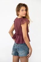 Woman wearing WYNONA polka dot chiffon crop top featuring lightweight printed chiffon, V-neckline with ruffle trim, flutter sleeves, elastic underbust band, front bow detail, and a cropped peplum silhouette with full lining for comfort.