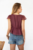 Woman wearing WYNONA polka dot chiffon crop top featuring lightweight printed chiffon, V-neckline with ruffle trim, flutter sleeves, elastic underbust band, front bow detail, and a cropped peplum silhouette with full lining for comfort.