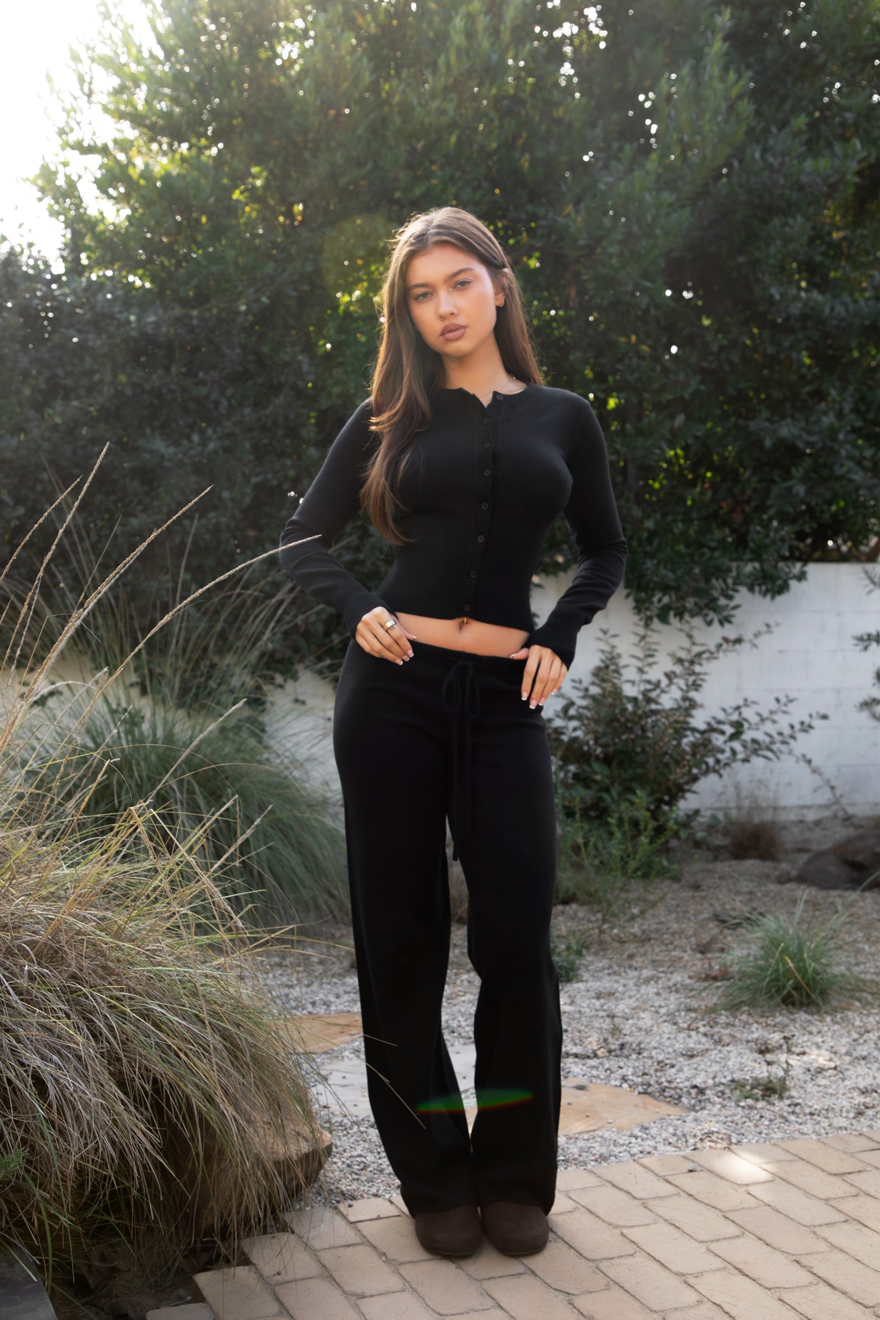 Woman wearing TIC TOC TPA31894-AVELYN AVELYN sweater knit pants set featuring a button front long sleeve ribbed cardigan with a slim cropped silhouette, paired with mid rise knit pants with waistband detail and a relaxed wide leg shape, styled as a cozy matching lounge set for everyday wear.
