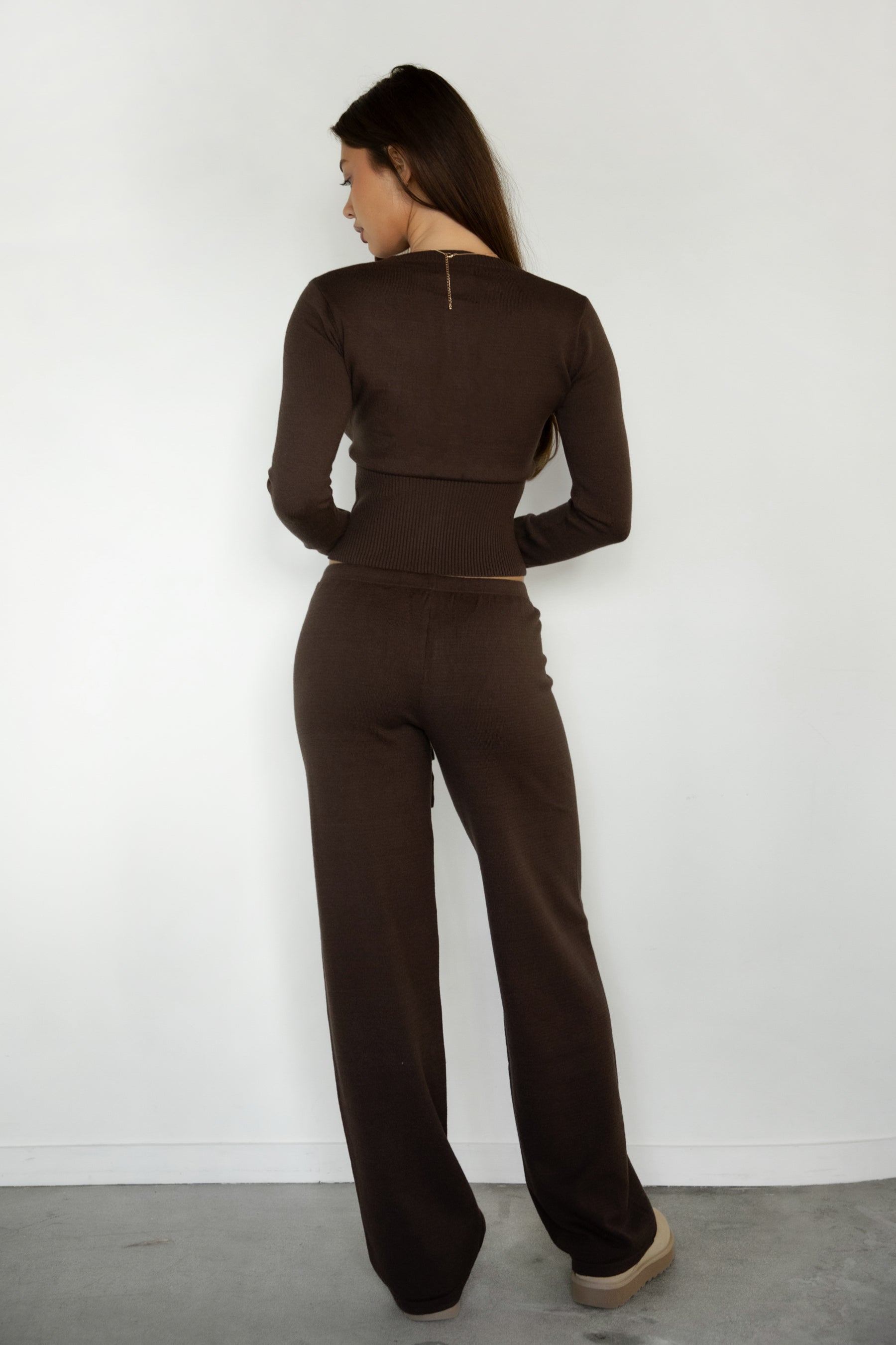 Woman wearing TIC TOC TPA31894-AVELYN AVELYN sweater knit pants set featuring a button front long sleeve ribbed cardigan with a slim cropped silhouette, paired with mid rise knit pants with waistband detail and a relaxed wide leg shape, styled as a cozy matching lounge set for everyday wear.