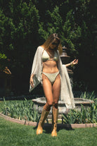 Woman wearing FLORRIE floral print triangle high leg bikini set featuring a classic triangle top with self tie halter neck and back closure, matching bottoms with adjustable side ties, high-leg cut, soft stretch swim jersey fabric, and fully lined construction for comfort and coverage.