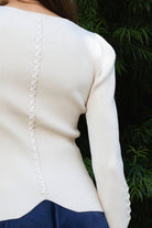 Woman wearing VIVIENNE lace up ribbed knit cardigan featuring fitted ribbed sweater knit fabric, soft scoop neckline, covered button front closure, long sleeves with subtle puff shoulder shaping, lace up detailing along the sleeve cuffs, decorative lace up detail down the center back, and slightly curved hem with fitted waist shaping.