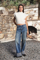 Woman wearing GARANCE mock neck sleeveless sweater top featuring a soft fuzzy knit texture, clean minimalist silhouette, polished mock neckline, relaxed bodice, subtle extended shoulder design, cropped length, wide ribbed hem, and solid color design for easy transitional layering.