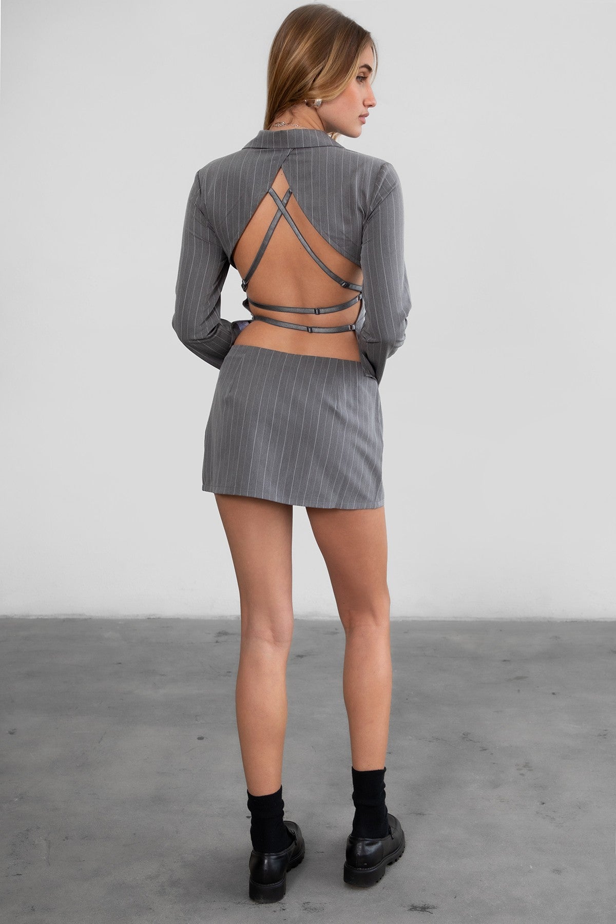 GEEK Pinstripe Mini Skirt Set 
Long Sleeve Top 
Low V Collared Neckline 
With Connected Hook and Eye Closure 
Slit Open Hem Design 
Full Open Back Design 
With Connected Criss Cross Adjustable Straps 
Matching Low Rise Mini Skirt