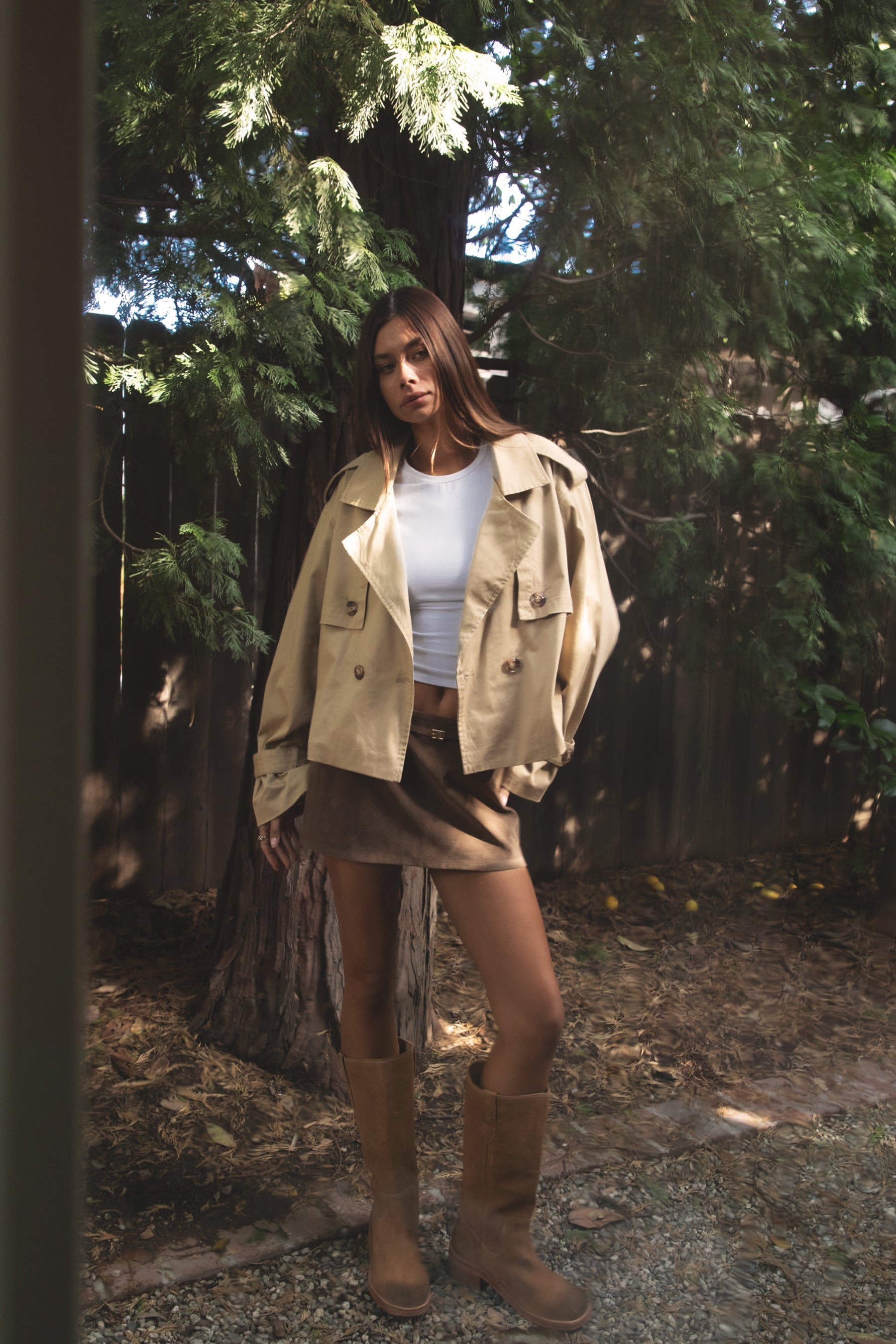 Woman wearing TIC TOC TT31828-MARAIS MARAIS oversized long sleeve cropped trench jacket featuring a double breasted front button closure, drop shoulder long sleeves with adjustable sleeve straps, removable thick self tie waist strap, and two loop holes on the back, finished with stripe voile lining inside, styled over a simple top and tailored bottoms for a Parisian chic, western-minimal layered look.