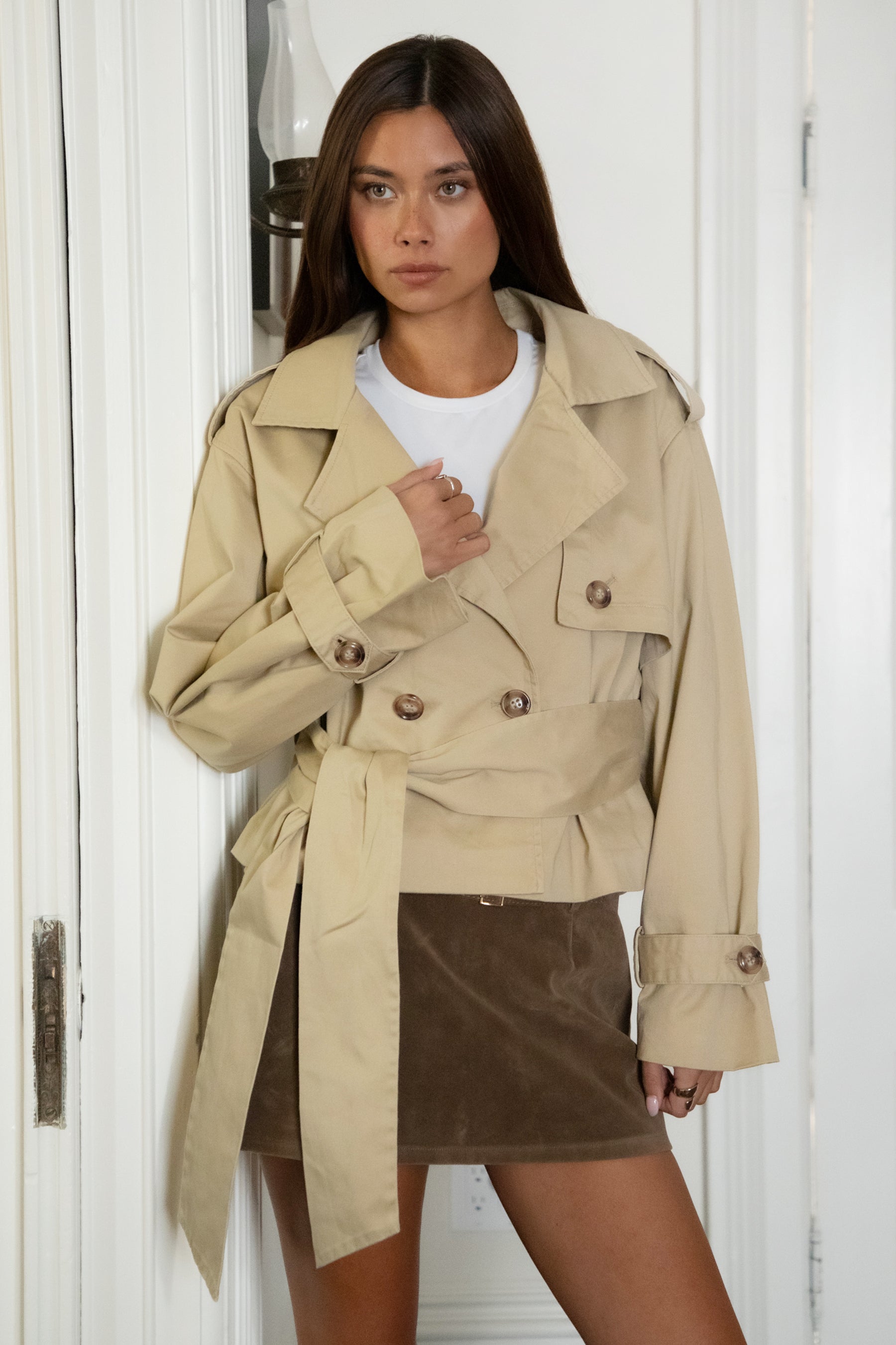 Woman wearing TIC TOC TT31828-MARAIS MARAIS oversized long sleeve cropped trench jacket featuring a double breasted front button closure, drop shoulder long sleeves with adjustable sleeve straps, removable thick self tie waist strap, and two loop holes on the back, finished with stripe voile lining inside, styled over a simple top and tailored bottoms for a Parisian chic, western-minimal layered look.