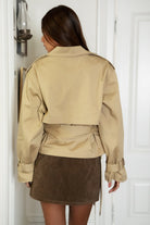 Woman wearing TIC TOC TT31828-MARAIS MARAIS oversized long sleeve cropped trench jacket featuring a double breasted front button closure, drop shoulder long sleeves with adjustable sleeve straps, removable thick self tie waist strap, and two loop holes on the back, finished with stripe voile lining inside, styled over a simple top and tailored bottoms for a Parisian chic, western-minimal layered look.