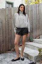 Woman wearing MARGOT plaid gingham zip up bomber jacket featuring lightweight crinkled cotton blend fabric, classic gingham plaid pattern, high neck collar, front button and zip closure, semi cropped length, sleeve snap buttons, relaxed drop shoulder silhouette, side pockets, and elastic hem.
